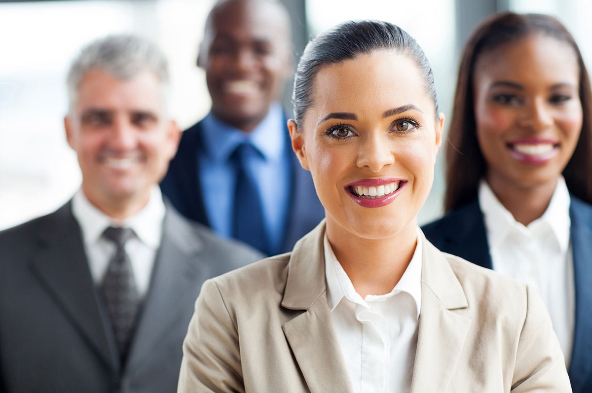 Four people smiling in a business environment, with a woman in focus