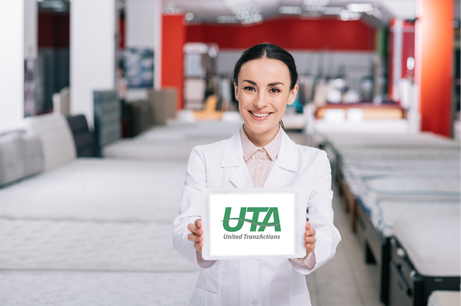 UTA's logo displayed on a tablet held by a woman in a mattress store