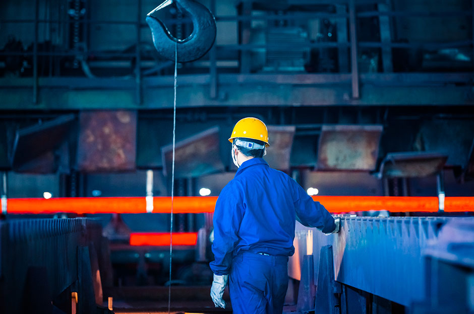 Worker wearing orange helmet observing the manufacturing warehouse