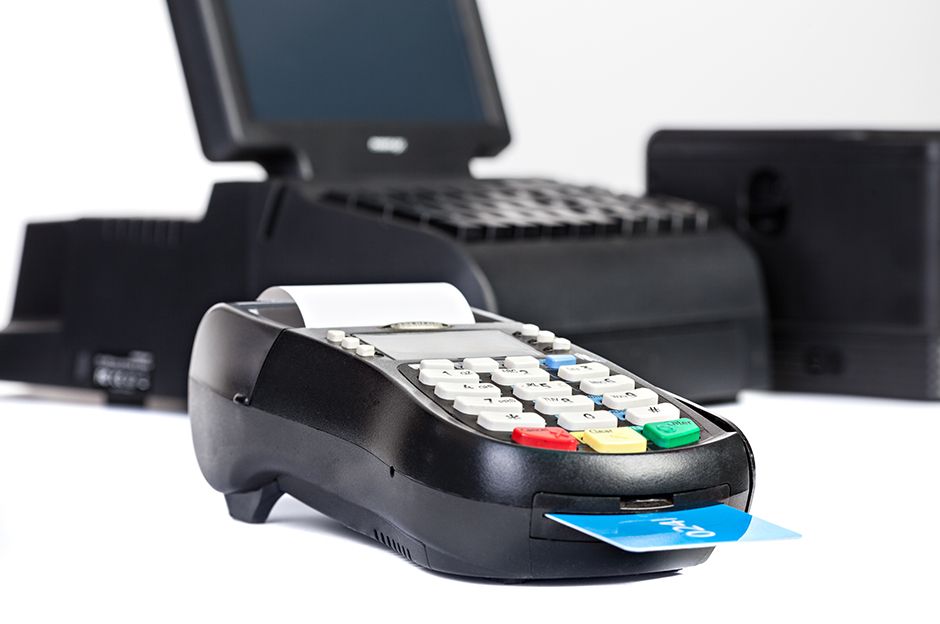 Close up of a POS terminal system with a credit card and receipt on top.