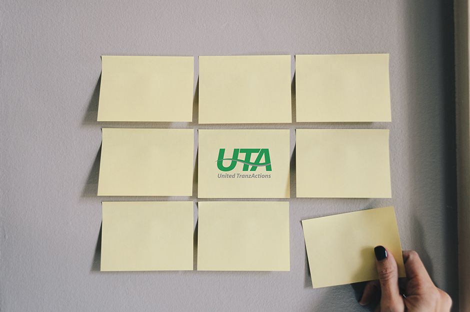 Hand placing the last sticky notes with UnitedTranzActions logo in the middle to complete the puzzle.