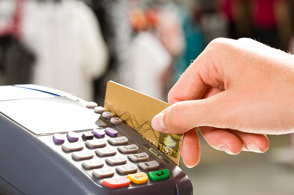 Hand swiping a credit card on a POS terminal