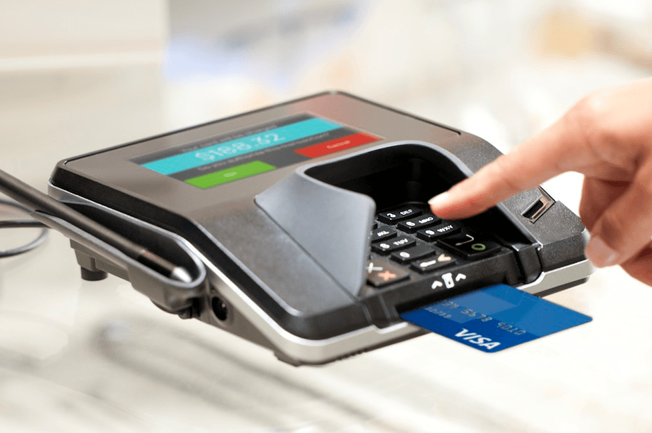 Hand pointing to numbers on a POS terminal with a VISA card inserted for payment